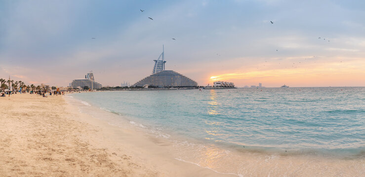 10 January 2026, Dubai, UAE: iconic Burj Al Arab hotel standing beside Jumeirah Beach with gulf waters during a colorful evening
