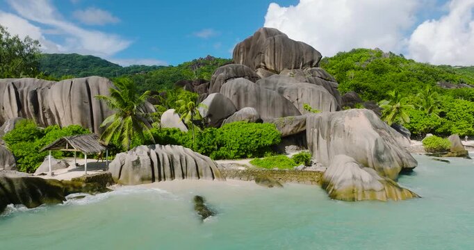 Granite rocks and dense greenery meeting the turquoise ocean on a sunny day. Anse Source d'Argent. Seychelles, La Digue.