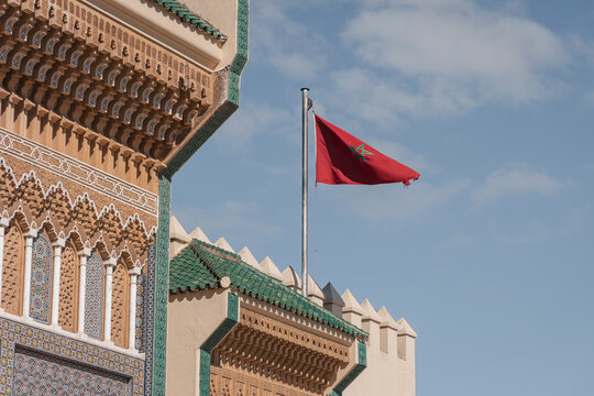 Moroccan flag flying over Dar al Makhzen, an iconic royal palace in Fes, showcasing Islamic architecture and traditional design
