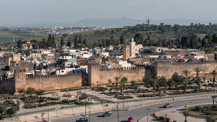 Fototapeta premium Fes ancient Medina city wall, architecture, and cityscape with a road and cars passing by in Morocco