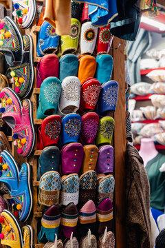 Handcrafted babouche slippers displayed in a market stall, showcasing diverse colors, patterns, and traditional Moroccan design