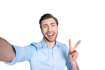 Naklejka premium Selfie mania. Close up of confident brunet student with beaming smile and beard taking a self-portrait on his mobile phone and showing v-sign while standing over grey background