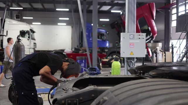 A dedicated service center worker skillfully employs welding techniques to repair a truck, ensuring safety and quality workmanship. The focused environment highlights professionalism and commitment.