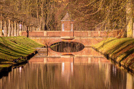 Die kleine Backsteinbr&uuml;cke spannt sich &uuml;ber das stille Wasser wie ein Satzzeichen in einem sehr alten Gedicht. Der Kanal tr&auml;gt das Licht behutsam weiter, als h&auml;tte er alle Zeit der Welt, und die Spieg