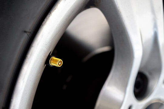 Macro shot of a car wheel rim highlighting a metallic tire valve stem - concept of automotive maintenance, pressure control, and vehicle detail