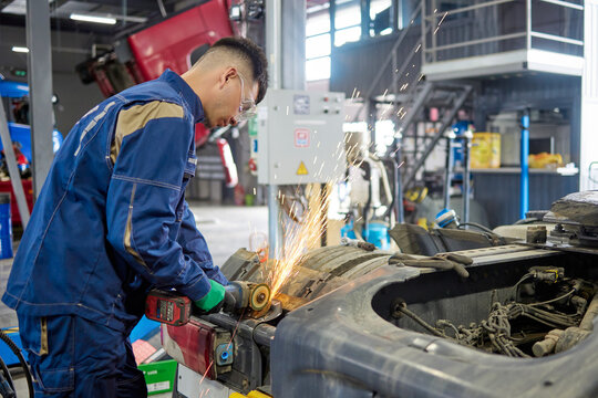 An expert truck repair technician skillfully uses a grinding machine to maintain heavy vehicles, highlighting the dedication and precision required in professional automotive maintenance.