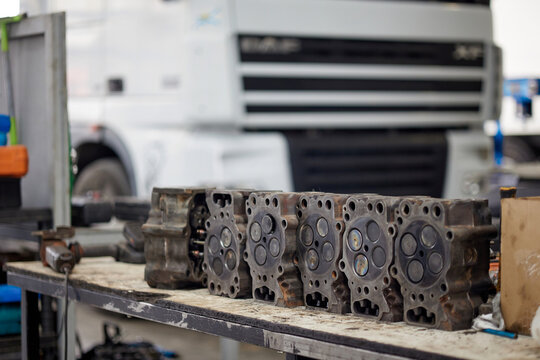 Mechanic repairing a truck engine with a focus on cylinder block heads. Well-equipped workshop with tools, showcasing professionalism in automotive services. Perfect for engine repair imagery.