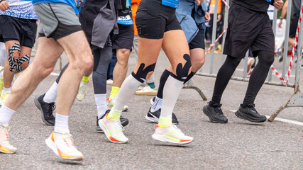 Fototapeta premium Athletes running on asphalt with sports injury support and colorful kinesio tapes