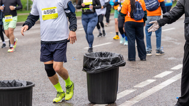 Runners passing by garbage cans at a city running event