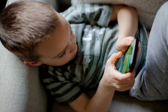Child young boy using smartphone playing game relaxed at home