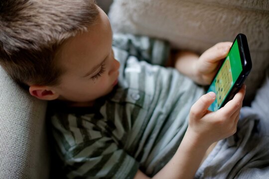Child young boy using smartphone playing game relaxed at home
