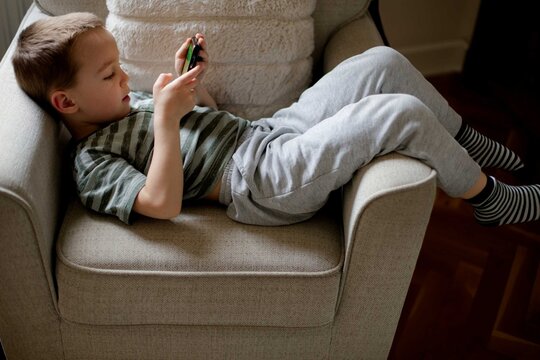 Child young boy using smartphone playing game relaxed at home