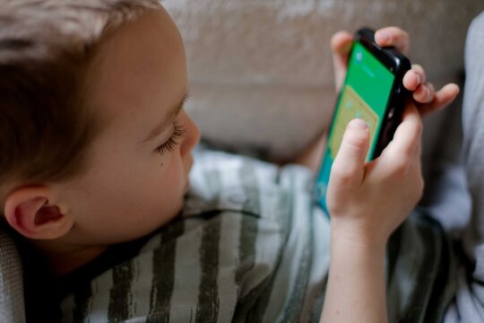 Child young boy using smartphone playing game relaxed at home