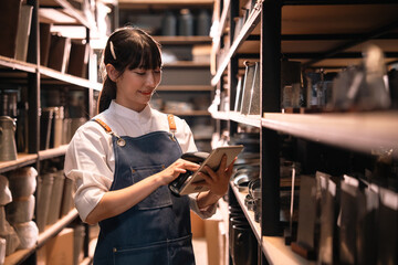 Young woman in apron using tablet in storage room © chokniti