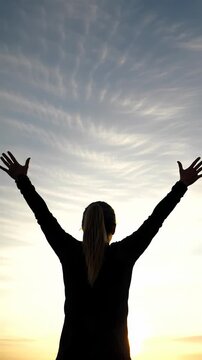 Lone figure with outstretched arms against a vibrant golden hour sky, bathed in warm light from a low angle, emphasizing joy and boundless potential concept of freedom and achievement