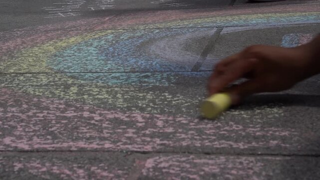 Zeitlupe Hand malt Regenbogen mit Kreide auf Boden im Sommer