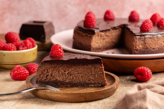 Pive of Oven baked Chocolate cheesecake with fresh raspberries. Homemade bakery on a brown table. Selective focus.