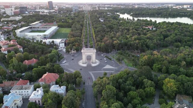 Bucharest, Romania - July 13, 2025. Aerial drone view of the Arch of Triumph monument and the nearby National Rugby Stadium. Cityscape featuring the historic landmark and sports arena.