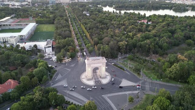 Bucharest, Romania - July 13, 2025. Aerial drone view of the Arch of Triumph monument and the nearby National Rugby Stadium. Cityscape featuring the historic landmark and sports arena.