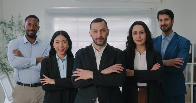 Portrait of multiethnic business team stands with arms crossed in corporate office. Multiracial finance professionals group collaborates for audit of company