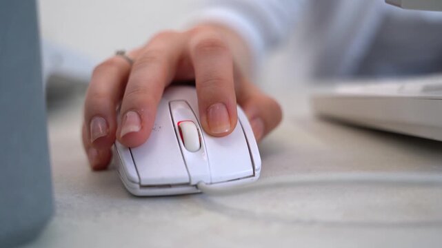 Close up of female hand using a white computer mouse on a light office desk professional worker navigating digital interface or editing content in workspace