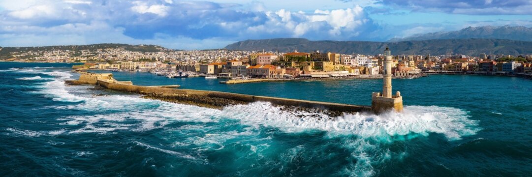Greece UHD panorama of Chania lighthouse with crushing waves in Crete. Aerial view of old Venetian port and harbor in Mediterranean sea. Iconic Greece travel landmark and historical scenic landscape.
