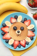 Naklejka premium Creative serving for kids. Cute lion made of pancake, banana and berries on table, flat lay