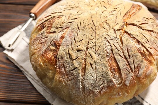 Loaf of freshly baked bread on wooden table, closeup