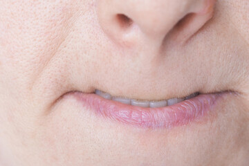 Fototapeta premium Mature Woman Pursing Lips With Slight Smile Showing Teeth In Extreme Close Up Lower Face Portrait Clinical Style Setting Focusing On Mouth Line Skin Texture And Nasolabial Detail.