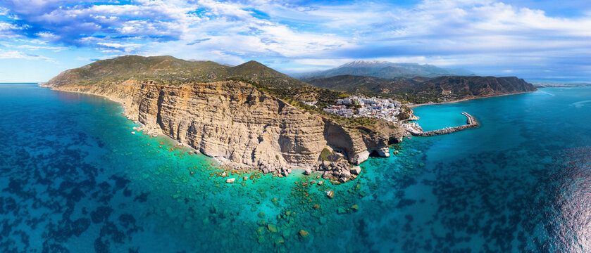 Crete Greece UHD panorama of Agia Galini with turquoise sea caves and snowy mountains. Aerial view of white coastal village in Mediterranean. Scenic winter landscape of Greek island and rocky cliffs