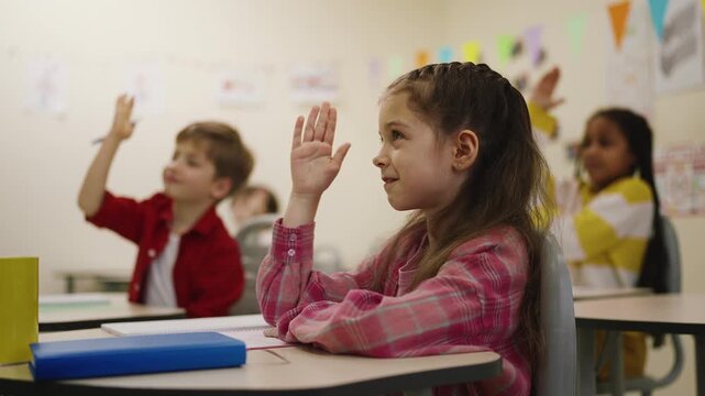 Primary school girl and classmates raising hands in teacher student interaction