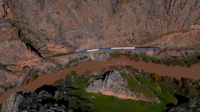 Aerial view of train winding through rugged, earthy valley (Dogu Ekspresi/Turkey)