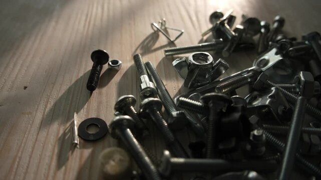 Scattered metal bolts and screws on wooden surface in sunlight