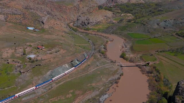 Aerial view of train winding through rugged, earthy valley (Dogu Ekspresi/Turkey)