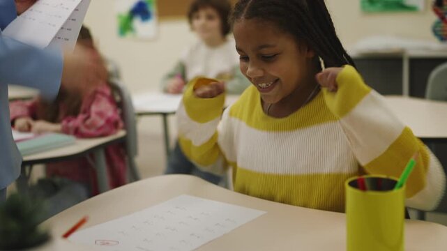 African American girl celebrating good test grade in classroom learning