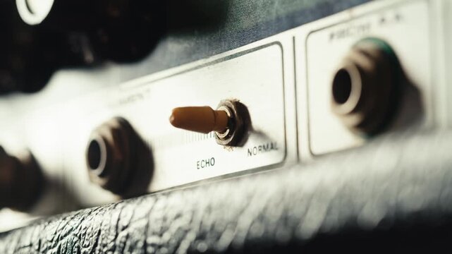 Close-up of plugging a jack into a bass guitar amplifier and turning up the volume knob, live concert show, playing music on guitar tube amplifier.