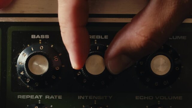 Close-up of plugging a jack into a bass guitar amplifier and turning up the volume knob, live concert show, playing music on guitar tube amplifier.