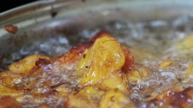 Gros plan sur du poulet frit en cuisson dans l&rsquo;huile bouillante, texture dor&eacute;e et croustillante