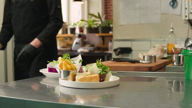 Chef cooking on professional kitchen in restaurant, making salad on plate, serving. Culinary preparation on kitchen.
