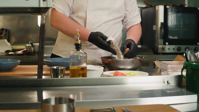 Chef cooking on professional kitchen in restaurant, making salad on plate, serving. Culinary preparation on kitchen.