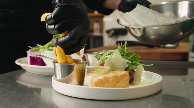 Chef cooking on professional kitchen in restaurant, making salad on plate, serving. Culinary preparation on kitchen.