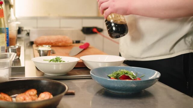 Chef cooking on professional kitchen in restaurant, making salad on plate, serving. Culinary preparation on kitchen.