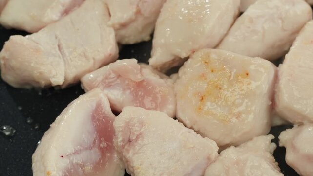 Man slicing raw turkey or chicken meat fillet on oak cutting board closeup, cooking with knife on restaurant kitchen.