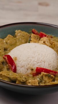 Green curry tofu soup cooking. Thai green curry soup in a white bowl on a white plate with dark background. Flat lay, overhead