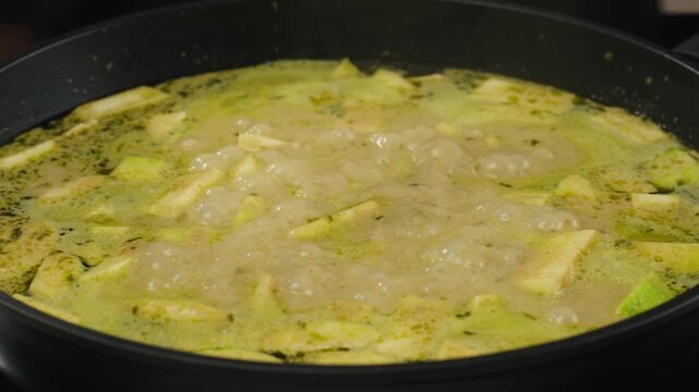 Green curry tofu soup cooking. Thai green curry soup in a white bowl on a white plate with dark background. Flat lay, overhead