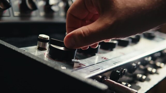 Music studio close up, Close up hands shot of sound engineer using mixing console, remote control for adjusting sound, audio mixer. Musician creates music, makes remix for DJ set. Sound recording