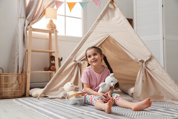 Little girl playing with toys near toy wigwam in playroom © New Africa
