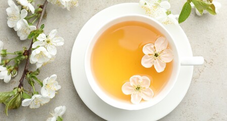 Naklejka premium Aromatic tea in cup and flowers on light grey table, flat lay