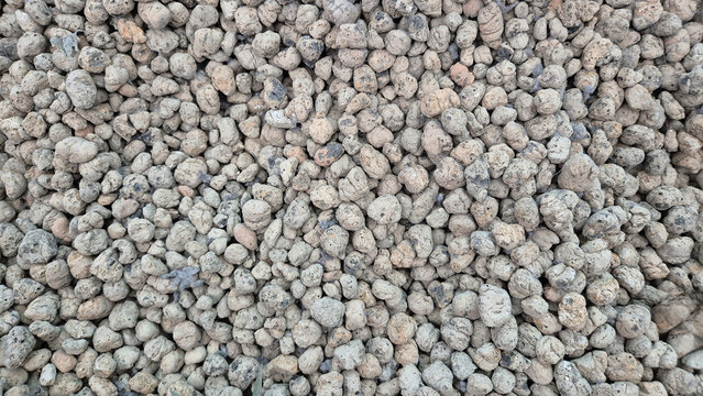 A top-down view of a dense pile of expanded clay aggregate pebbles, showing varied textures, earthy tones, and small, rounded volcanic-like stones.