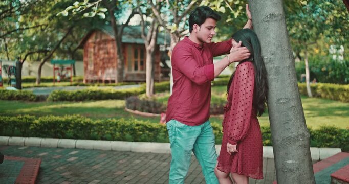 A boy gently touches the girl&rsquo;s hair as she tries to walk away, but he stops her; the couple shares an emotional eye contact in the garden. A sweet romantic interaction showing attraction, bonding